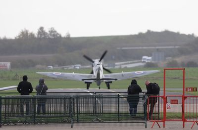 Rear view of people at airport runway against sky