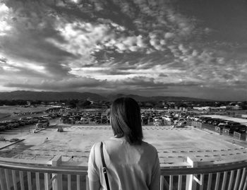 Rear view of woman looking at cityscape against sky