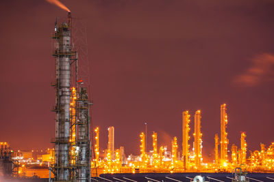 Illuminated factory against sky at night