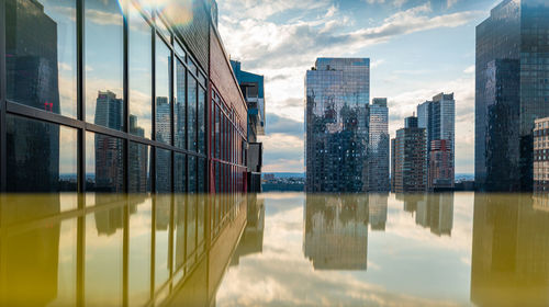 Reflection of buildings on glass against sky