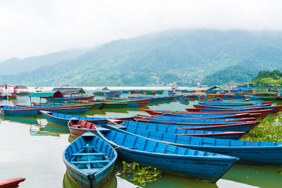 Boats moored in lake against mountains