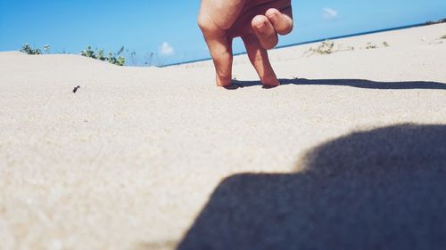 Cropped hand on sand at beach