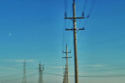 Low angle view of electricity pylon against blue sky