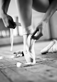 Low section of ballerina tying ballet shoes