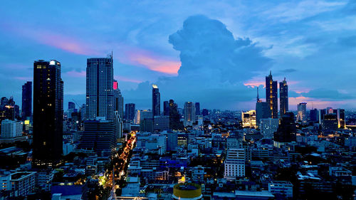 Illuminated buildings in city against sky at dusk