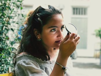 Young woman holding hand mirror while standing outdoors