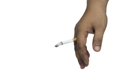 Close-up of hand holding cigarette against white background