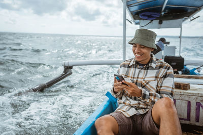 Rear view of man sitting on boat in sea