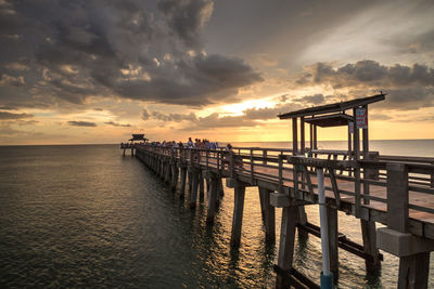 Pier over sea against sky during sunset