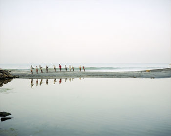 Rear view of fishermen pulling fishing net at beach