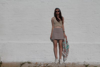 Portrait of young woman standing against wall