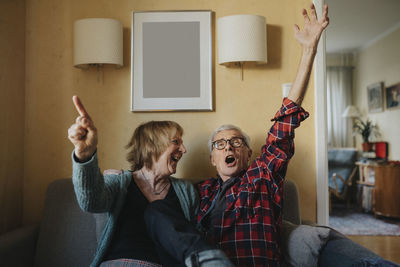 Senior couple sitting on sofa and singing