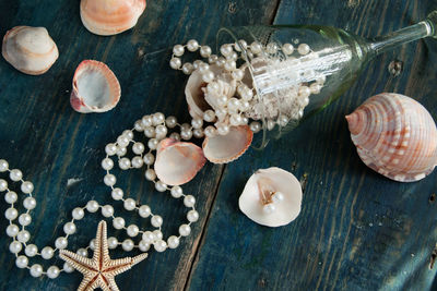 Directly above shot of pearls with wineglass and seashells on wooden table