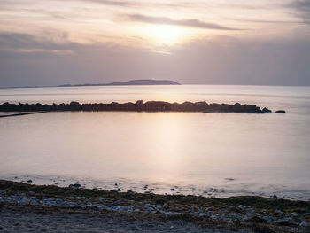 Romantic sunset with hiddensee view from dranske, rugen island. mossy breakwaters. moody pink sky