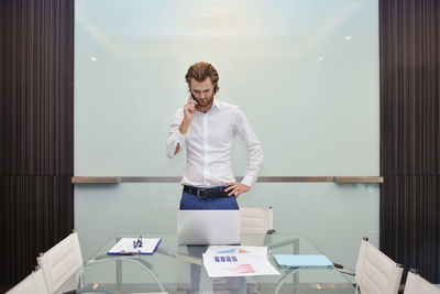 Businessman talking on smart phone while standing in conference room