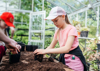 Young gardeners transplanting plants in greenhouse