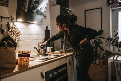 Young woman making tea in kitchen at home