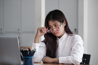 Young woman using phone while sitting on table