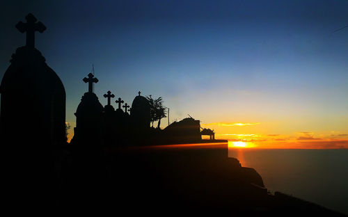 Silhouette statue by sea against sky during sunset