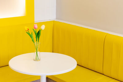Flower vase on table against yellow wall at home