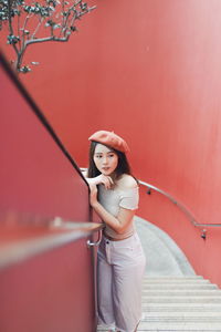 High angle view of young woman standing on staircase against red wall