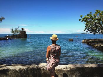 Rear view of woman standing by sea against clear sky