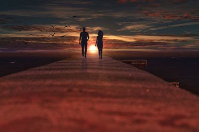 Silhouette couple walking on pier against sky during sunset