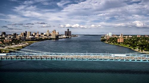 Ambassador bridge over detroit river against sky in city