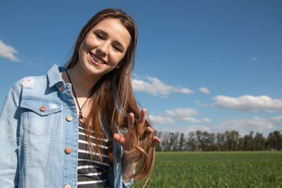 Portrait of young woman standing against sky