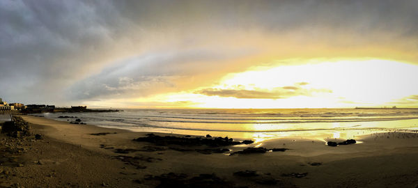 Scenic view of beach against dramatic sky