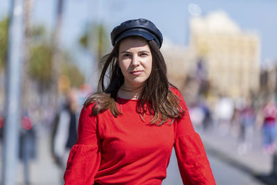 Portrait of teenage girl wearing red top in city during sunny day