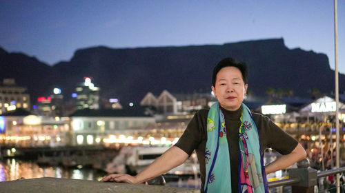 Portrait of man standing against illuminated city at night
