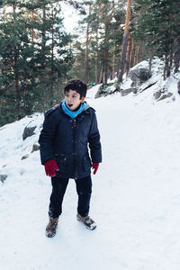 Full length portrait of happy boy standing on snow field