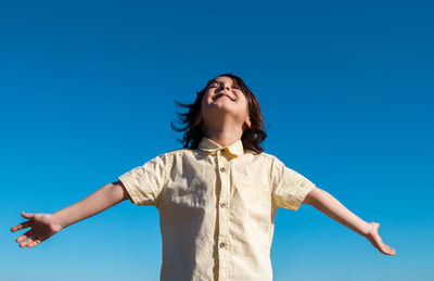 Low angle view of woman standing against blue sky