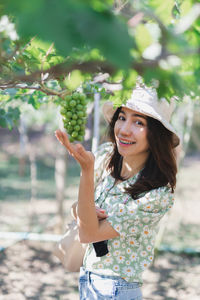 Young woman holding fruit while standing outdoors