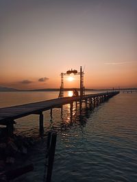 Pier over sea against sky during sunset