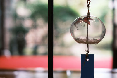 Close-up of electric lamp hanging on glass building