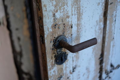 Close-up of rusty doorknob on weathered door