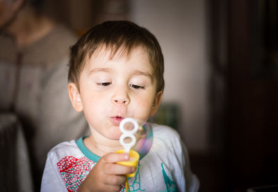 Playful boy blowing bubbles at home