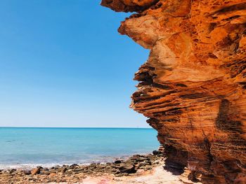 Rock formation on beach against clear blue sky