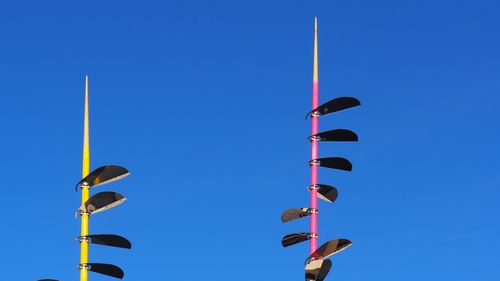 Low angle view of flags against clear blue sky