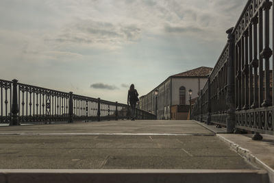 Man on road amidst buildings against sky in city