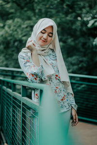 Young woman standing against railing