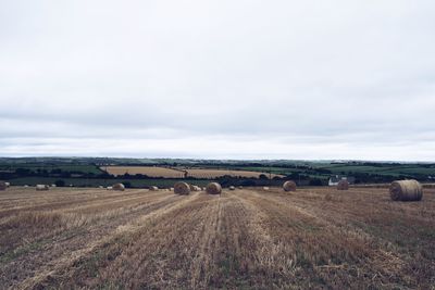 Hay bales on field against sky