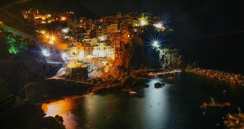 Illuminated buildings by sea at night