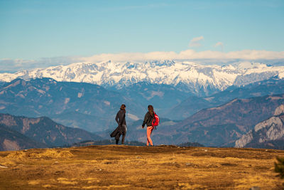 Rear view of people walking on snowcapped mountain against sky