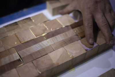 Cropped hand of carpenter touching wood at workshop