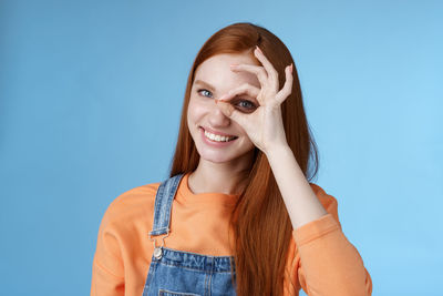 Portrait of smiling young woman against blue background