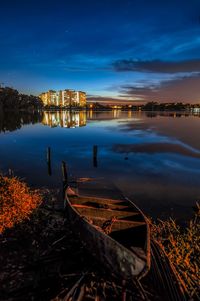 Scenic view of lake by buildings against sky at dusk