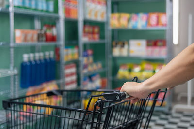 Cropped hand of woman holding shopping cart in supermarket